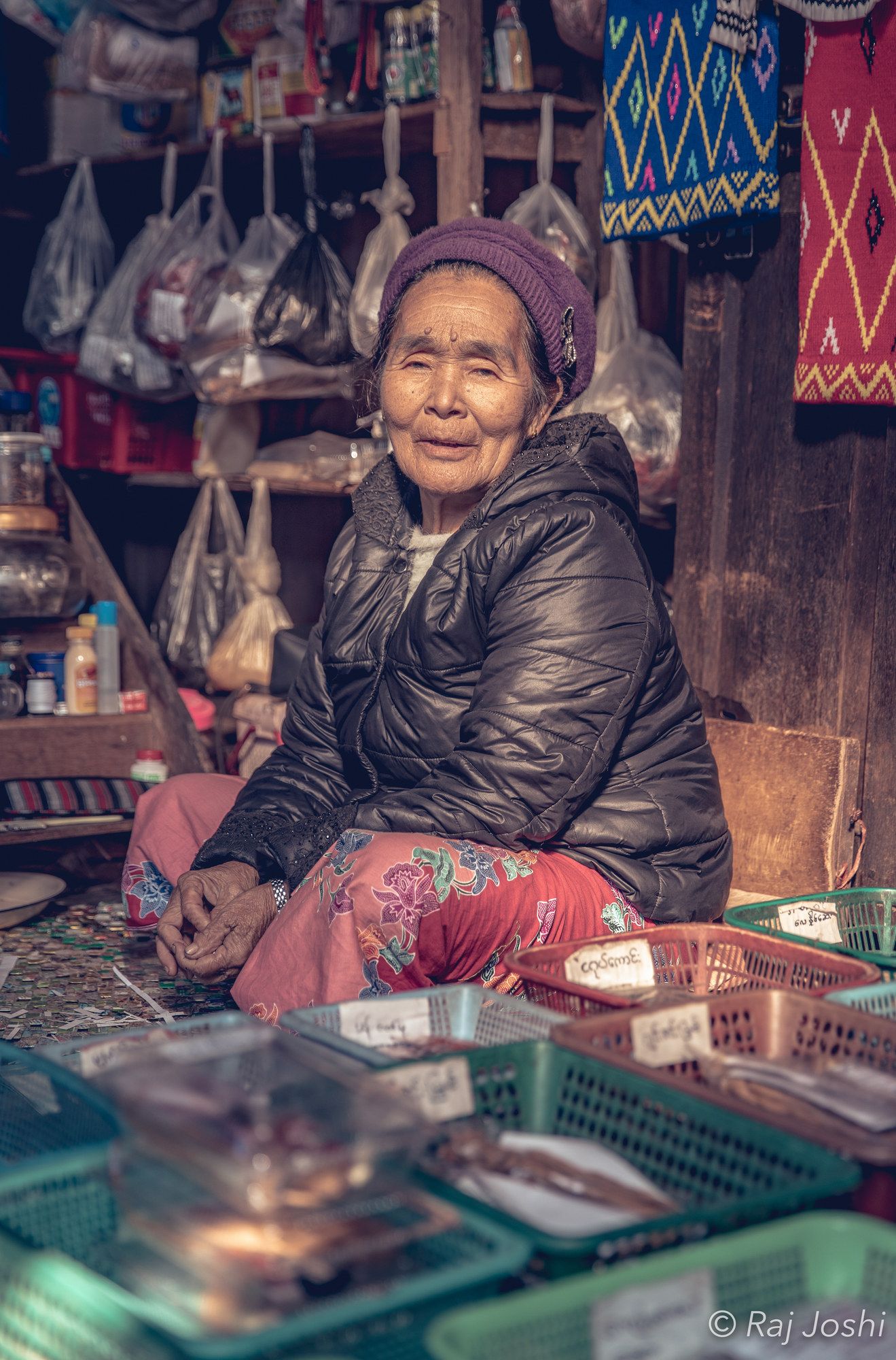 A woman seated among woven baskets in a dim covered market