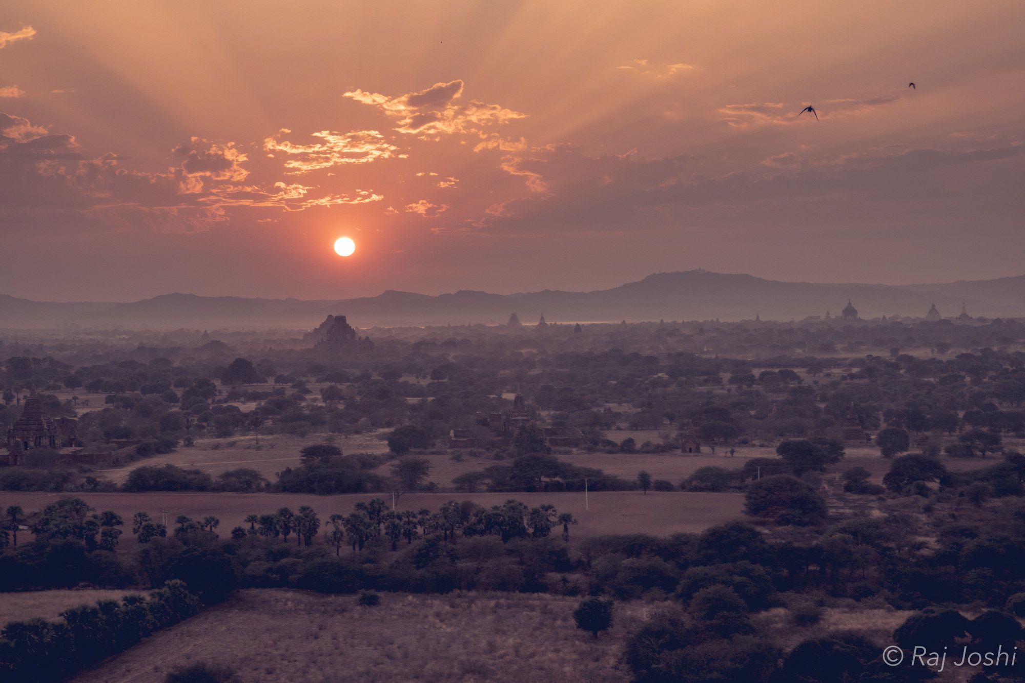 The sun breaking through mist over the stupas of the Bagan plain