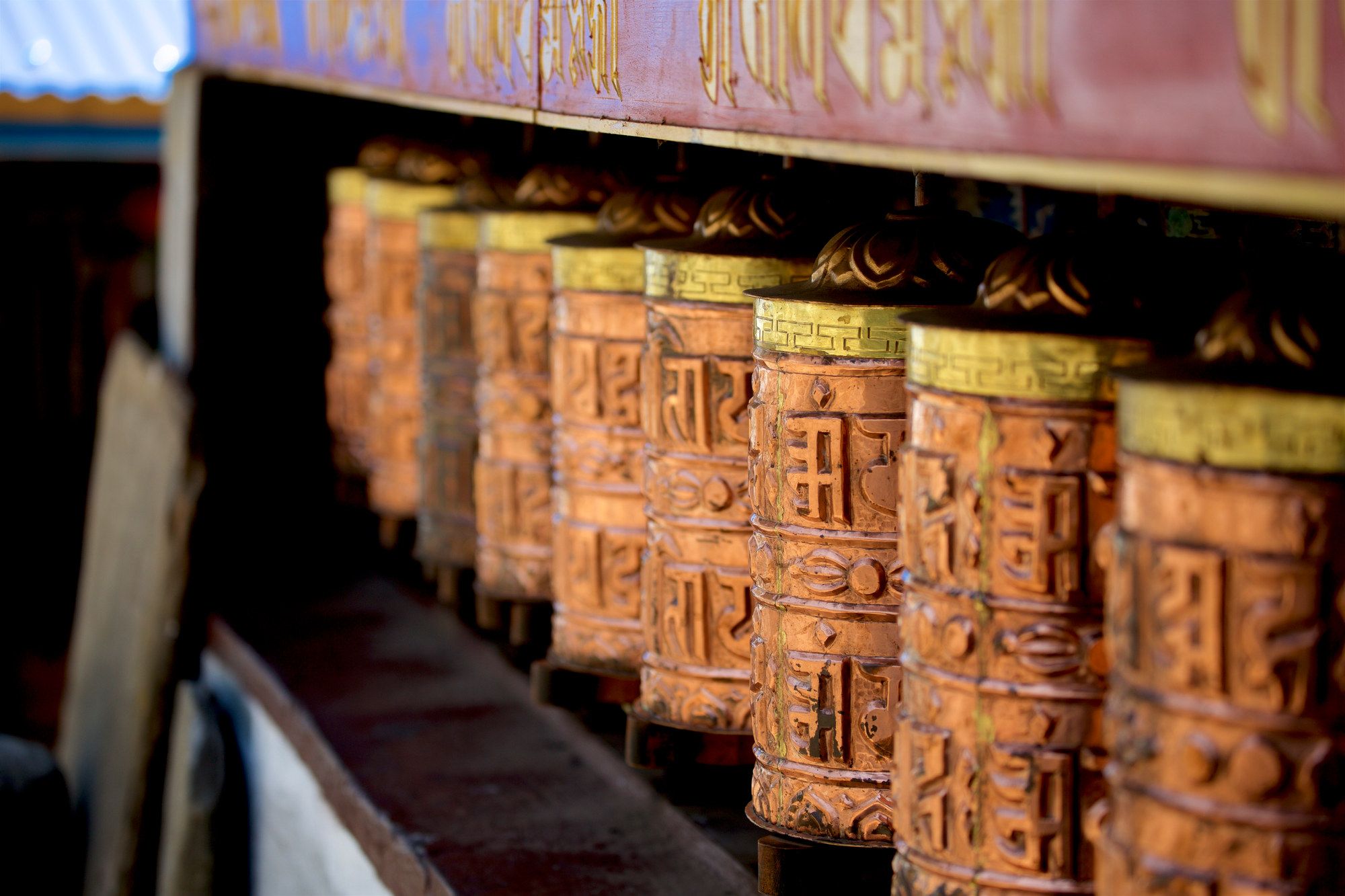 A row of brass prayer wheels worn bright by countless passing hands